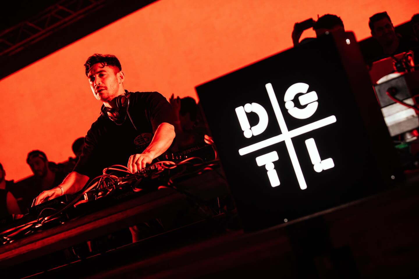 A DJ playing at DGTL, the festival’s logo lit beside the booth