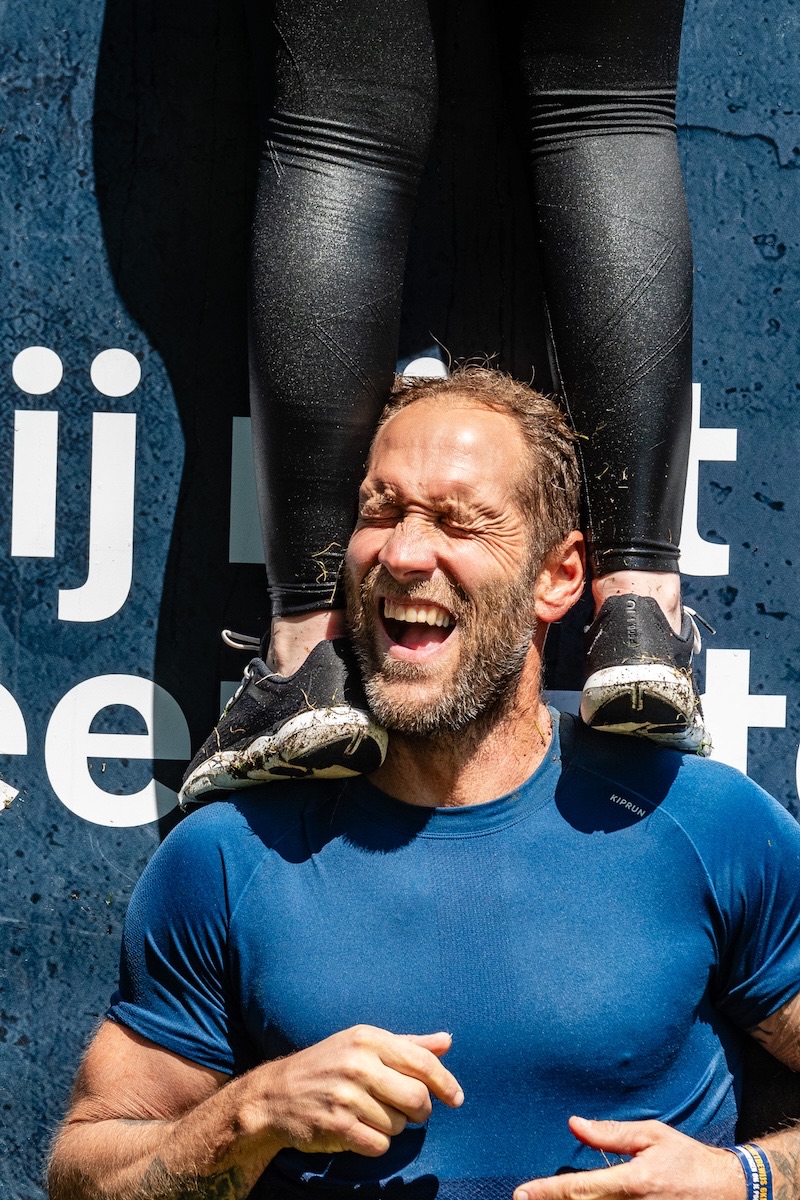 A Mud Masters participant lifting a teammate over an obstacle